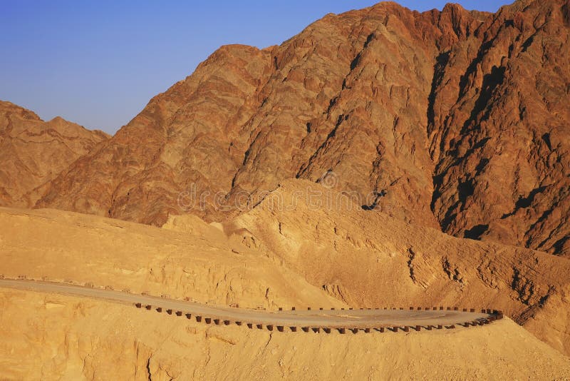 Les montagnes rouges de l'Arava abandonnent dans le coucher de soleil Montagne Solomon et route de montagne photo libre de droits Les montagnes rouges de l'Arava abandonnent dans le coucher de soleil Montagne Solomon et route de montagne photo libre de droits