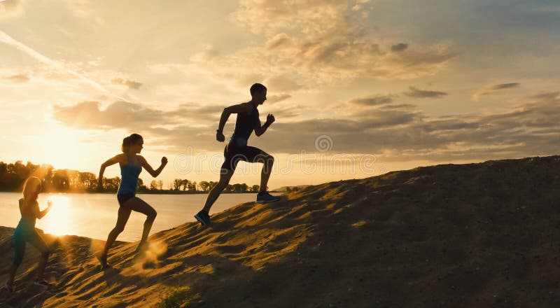 Les motivations de sport - groupe d'athlètes - deux filles et un type se sauvent la montagne, près de la rivière au crépuscule image libre de droits Les motivations de sport - groupe d'athlètes - deux filles et un type se sauvent la montagne, près de la rivière au crépuscule image libre de droits