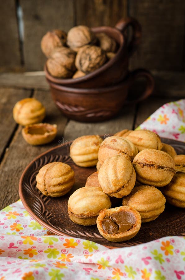 Les noix forment des biscuits avec du lait condensé - dulce de leche dans la cuvette d'argile sur le fond rustique en bois Foyer image libre de droits Les noix forment des biscuits avec du lait condensé - dulce de leche dans la cuvette d'argile sur le fond rustique en bois Foyer image libre de droits