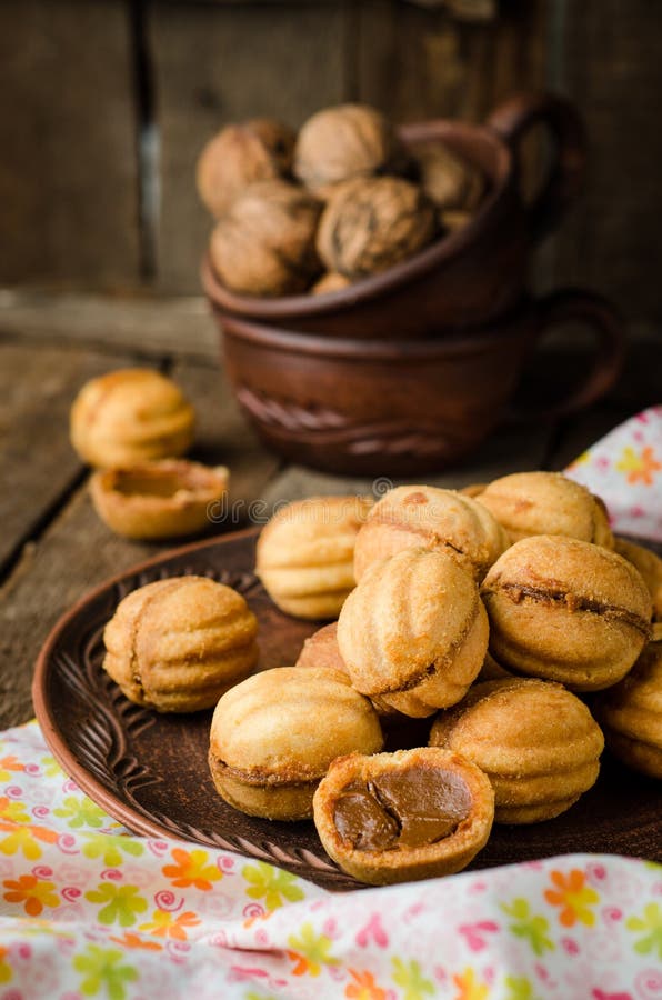 Les noix forment des biscuits avec du lait condensé - dulce de leche dans la cuvette d'argile sur le fond rustique en bois Foyer photo libre de droits Les noix forment des biscuits avec du lait condensé - dulce de leche dans la cuvette d'argile sur le fond rustique en bois Foyer photo libre de droits