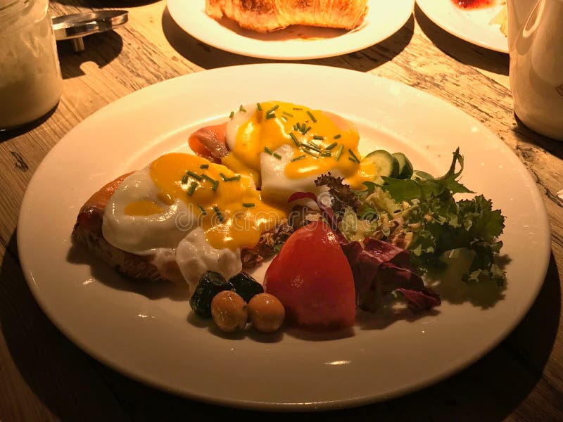 Les oeufs Benoît avec les saumons fumés sur le pain rôti ont servi avec l'huile d'olive, les tomates et la salade fraîche photos stock Les oeufs Benoît avec les saumons fumés sur le pain rôti ont servi avec l'huile d'olive, les tomates et la salade fraîche photos stock