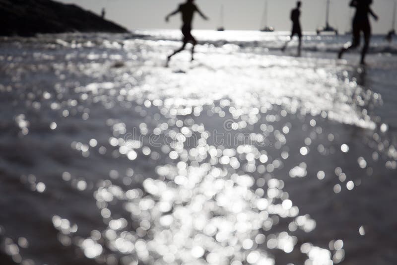 Les personnes de tache floue détendent sur le bokeh tropical de plage et d'eau de coucher du soleil photos stock Les personnes de tache floue détendent sur le bokeh tropical de plage et d'eau de coucher du soleil photos stock