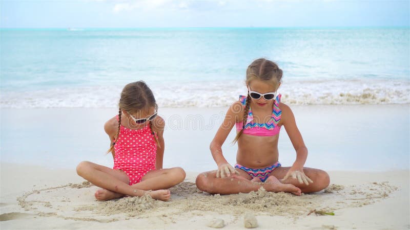 Les petites filles adorables ont beaucoup d'amusement sur la plage Deux beaux enfants jouant avec le sable sur le bord de la mer banque de vidéos