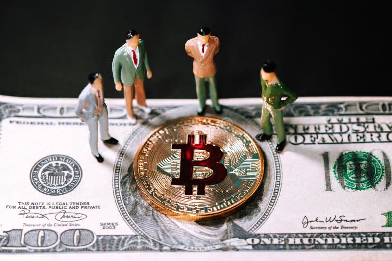 Les petits chiffres hommes d'affaires de personnes miniatures se tiennent et semblant le bitcoin d'or sur cent billets de banque photos stock Les petits chiffres hommes d'affaires de personnes miniatures se tiennent et semblant le bitcoin d'or sur cent billets de banque photos stock