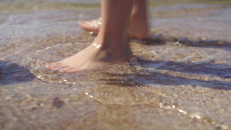 Les pieds nus marchent le long du rivage  Ramasse un char noir jeté par le surf