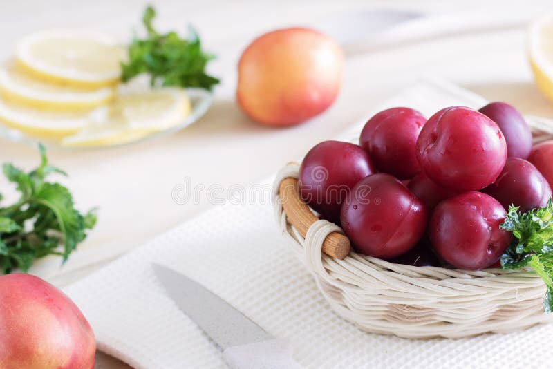 Les prunes juteuses se situent dans un panier sur la table près des pêches juteuses et du citron coupé en tranches, nourritures d photo libre de droits Les prunes juteuses se situent dans un panier sur la table près des pêches juteuses et du citron coupé en tranches, nourritures d photo libre de droits