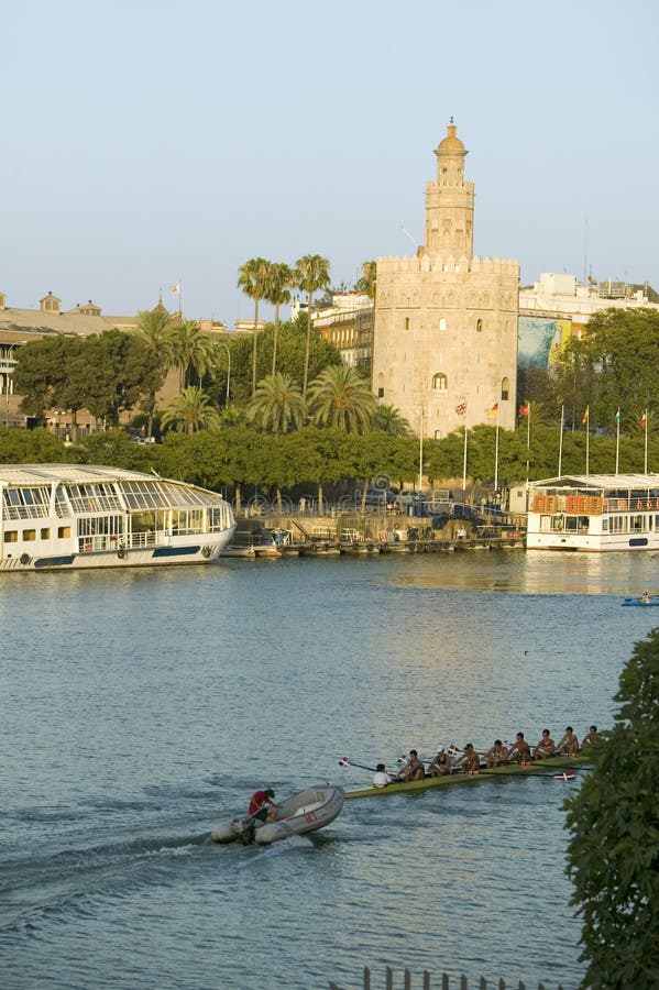 Les rameurs rament par la tour octogonale de Torre del Oro fait la réflexion d'or sur Canal de Alfonso de Rio Guadalquivir River, images stock Les rameurs rament par la tour octogonale de Torre del Oro fait la réflexion d'or sur Canal de Alfonso de Rio Guadalquivir River, images stock
