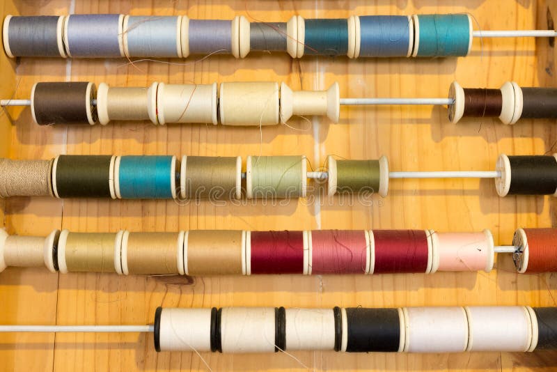 Les rangées de couleur de couture filète le cadre sur la table en bois photographie stock libre de droits Les rangées de couleur de couture filète le cadre sur la table en bois photographie stock libre de droits