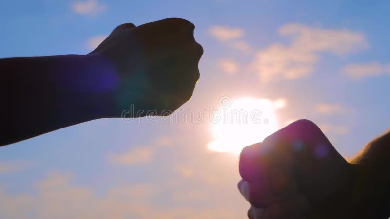 Les silhouettes des mains de l'homme et de la femme se bousculent les poings contre le ciel avec le soleil clips vidéos