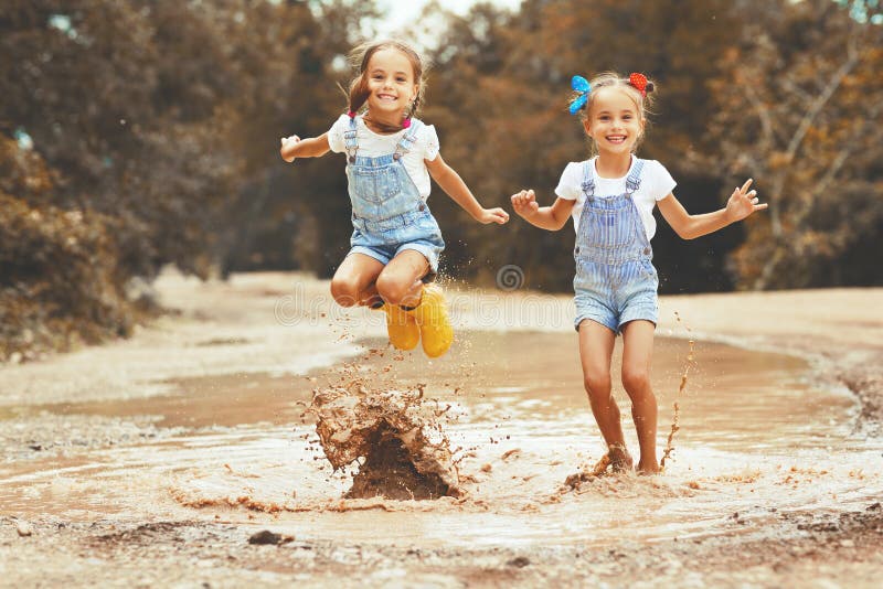 Les soeurs drôles heureuses jumelle la fille d'enfant sautant sur des magmas dans la bande de frottement image stock Les soeurs drôles heureuses jumelle la fille d'enfant sautant sur des magmas dans la bande de frottement image stock
