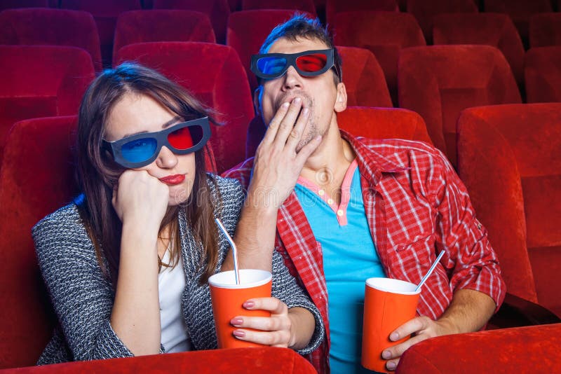 The spectators sitting in the cinema and watching movie with cups of cola and popcorn. Concept of a variety of human emotions. The spectators sitting in the cinema and watching movie with cups of cola and popcorn. Concept of a variety of human emotions.