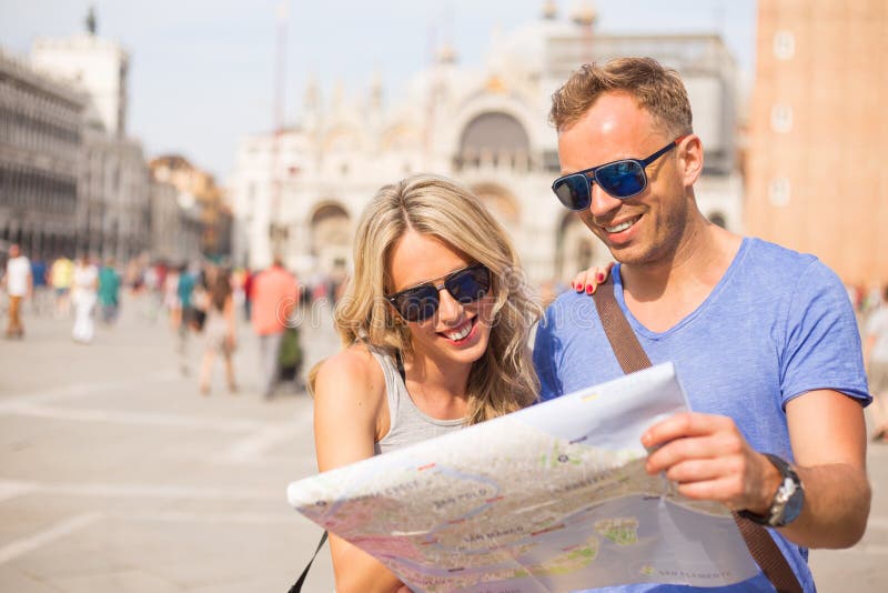 Les touristes couplent regarder la carte de ville photographie stock libre de droits Les touristes couplent regarder la carte de ville photographie stock libre de droits