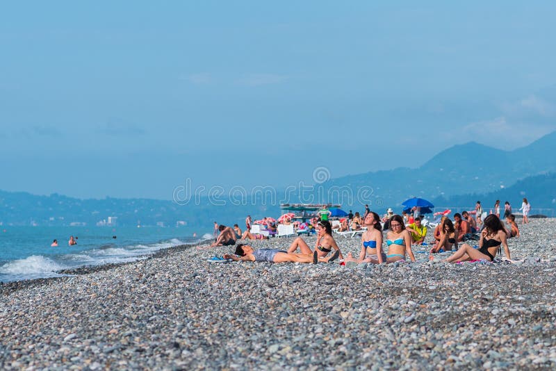 Les touristes (jeunes femmes) les prennent un bain de soleil sur la plage de Batumi images stock Les touristes (jeunes femmes) les prennent un bain de soleil sur la plage de Batumi images stock
