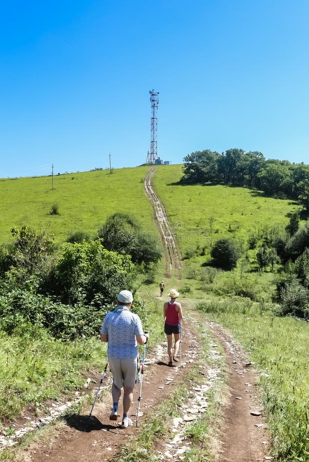 Les touristes marchent le long de la route à la tour de communications sur a images libres de droits Les touristes marchent le long de la route à la tour de communications sur a images libres de droits