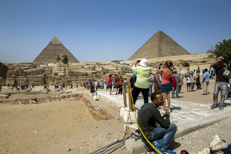 Tourists take photographs of the magnificent view showing the Sphinx, the Pyramid of Khafre (left) and the Pyramid of Khufu (right) at Giza in Cairo, Egypt. Tourists take photographs of the magnificent view showing the Sphinx, the Pyramid of Khafre (left) and the Pyramid of Khufu (right) at Giza in Cairo, Egypt.