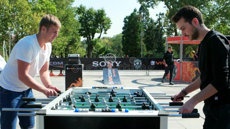 Les types jouant le football de table, extérieur intéressant, jeux de renforcement d'équipe, amis ont l'amusement ensemble