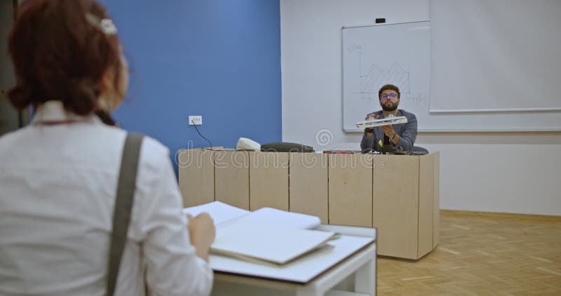 Les élèves écoutent attentivement en classe pendant que l'enseignant explique un modèle architectural complexe. clips vidéos