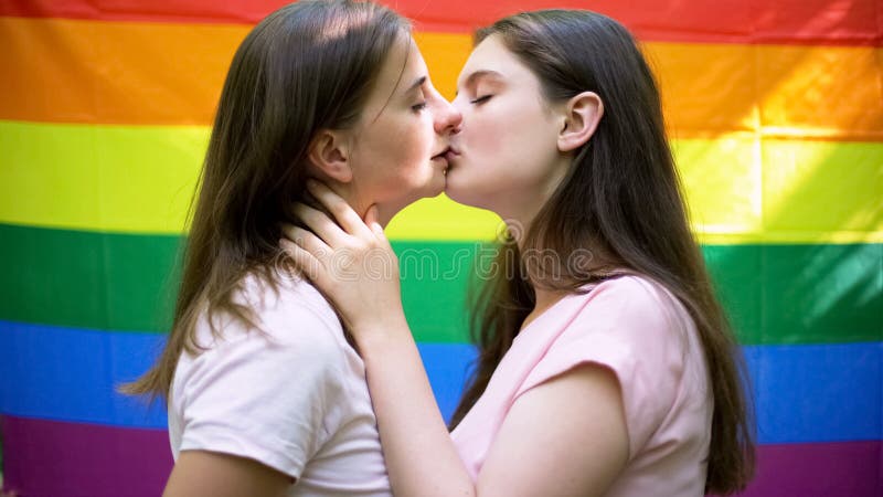 Lesbian couple kissing on rainbow flag background, same-sex relationship, love, stock photo