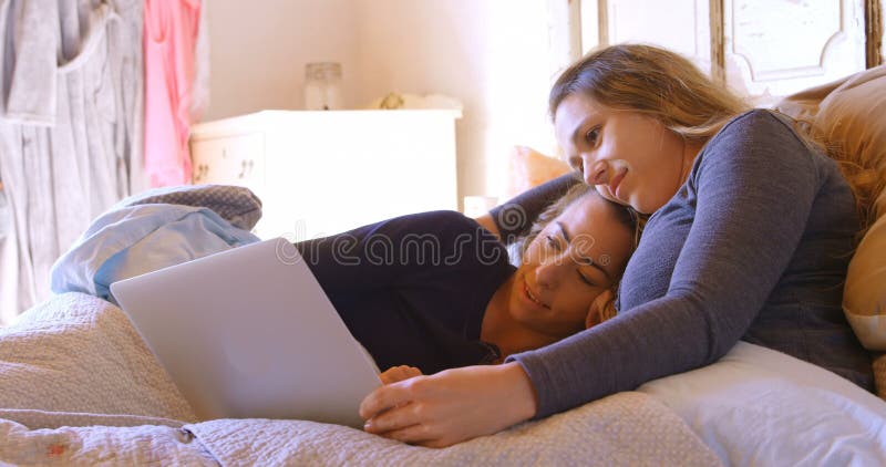 Lesbian couple using laptop in bedroom 4k