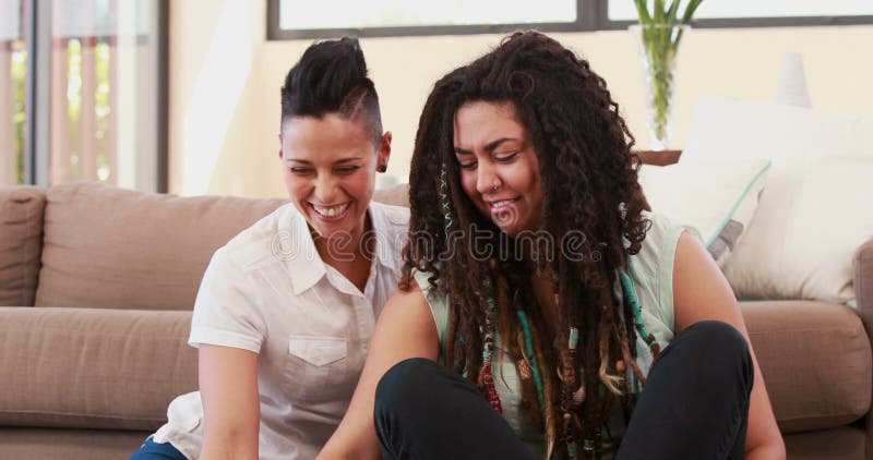 Lesbian couple using laptop while siting on the floor