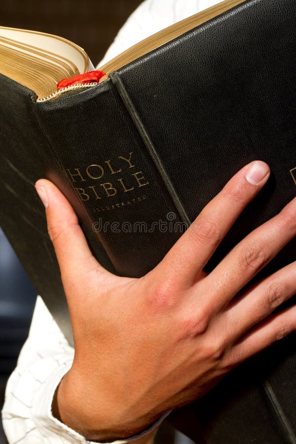 A close up of a man holding the holy bible. A close up of a man holding the holy bible