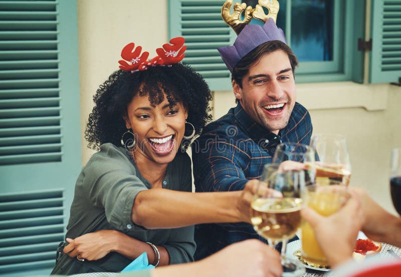 Let the good times roll. a beautiful young couple joining their glasses for a toast at a Christmas lunch party.