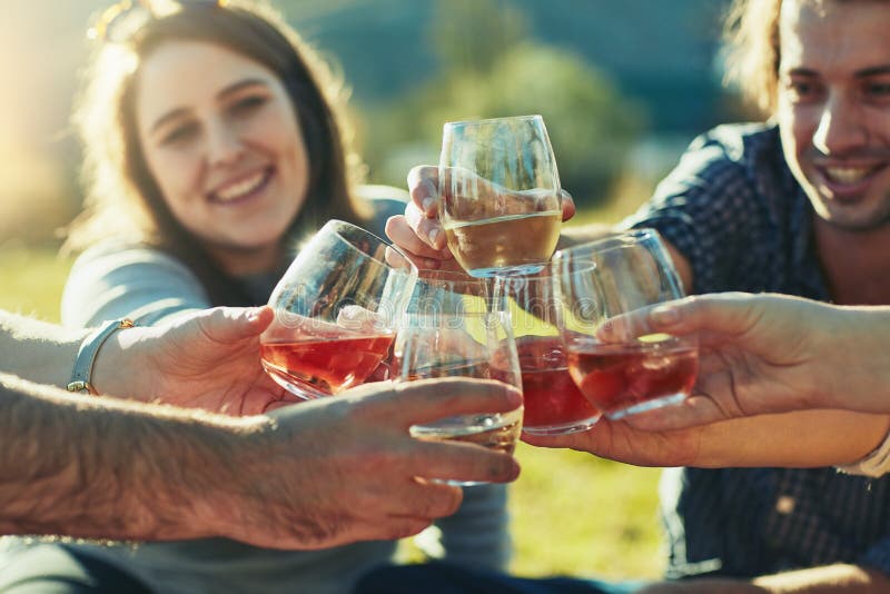 Let the good times roll. a group of friends toasting with their drinks outdoors.