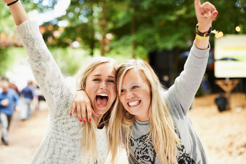 Let the good times roll. Portrait of a two young blonde friends embracing and cheering while outside at a festival.
