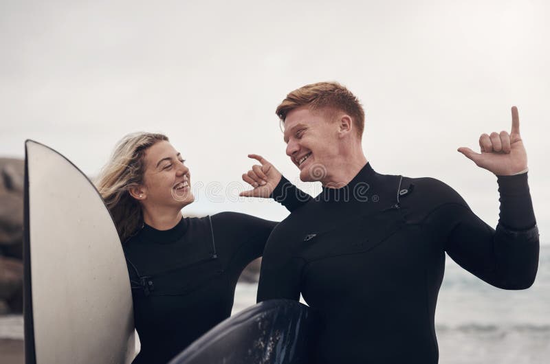 Let the good times roll. a young couple out at the beach with their surfboards.