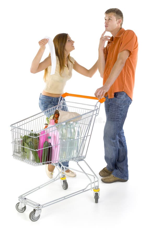 Young couple with trolley. Discussing about shop bill. Boy thinking about something and smiling, girl is angry. Isolated on white in studio, whole body. Smiling asking stock images, royalty-free photos and pictures