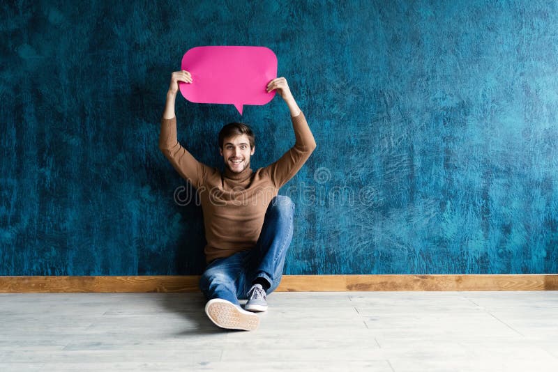 Let`s start a conversation. I speak the language of success. Handsome young man holding up speech bubble  on