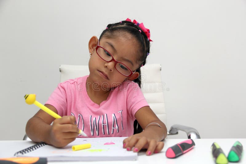 4-letnia brunetka latina dziewczyna z zaburzeniami autyzmu, jak asperger rett i heller rysuje na biurku bawi się kolorem. 4-letnia brunetka latina dziewczyna z zaburzeniami autyzmu, jak asperger rett i heller przyciąga do biurka