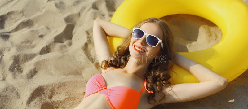 Letnie wakacje szczęśliwa relaksująca młoda kobieta leżąca na piasku na plaży z pływającym nadmuchiwanym pierścieniem zdjęcia stock