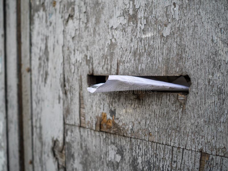 A letra amarrotada encontra-se em uma caixa postal Uma cerca de madeira velha com uma caixa postal fotografia de stock A letra amarrotada encontra-se em uma caixa postal Uma cerca de madeira velha com uma caixa postal fotografia de stock