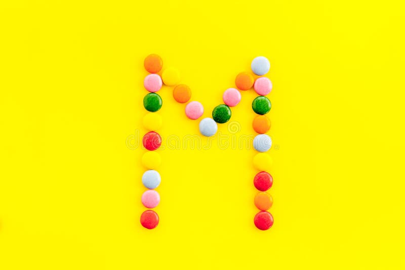 Letter M Alphabet Made with Sweets on Yellow from Above Stock Photo