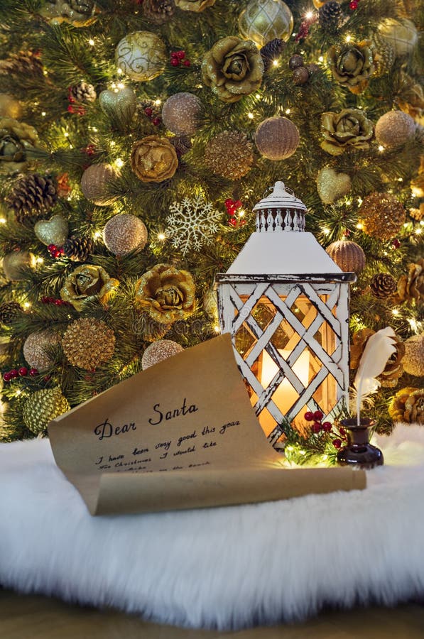 Letter for Santa Claus, ink pen in inkpot and lantern with burning candle against decorated Christmas tree. Child wish list