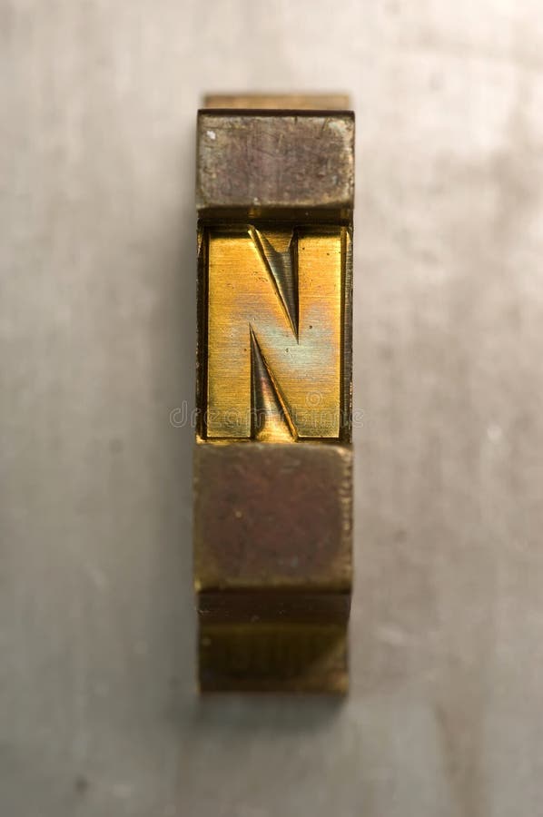 Brass / Gold colored letterpress piece on silver metal background. Metal n stock images, royalty-free photos and pictures