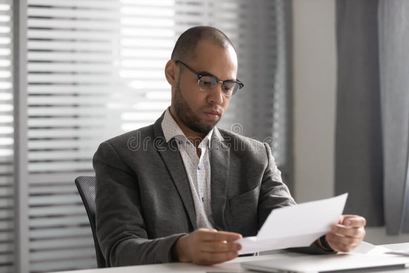 Lettre masculine ciblée de papier de lecture des travailleurs sur le lieu de travail photographie stock
