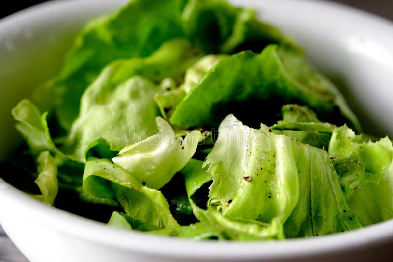 Lettuce with dressing and freshly ground, black pepper in a white salad bowl. Addition salad stock images, royalty-free photos and pictures