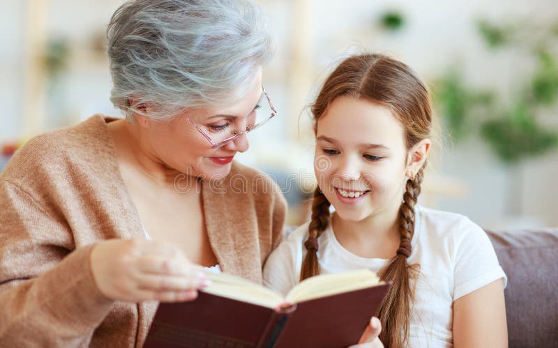 Lettura felice della nonna della famiglia al libro della nipote a casa