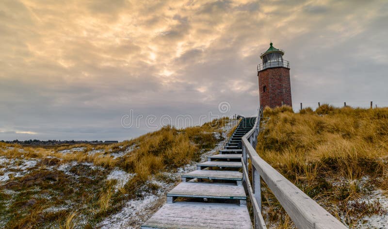 Leuchtturm auf einer Düne mit weichem Schnee aus Holztreppen und umliegendem Gras. stockfoto