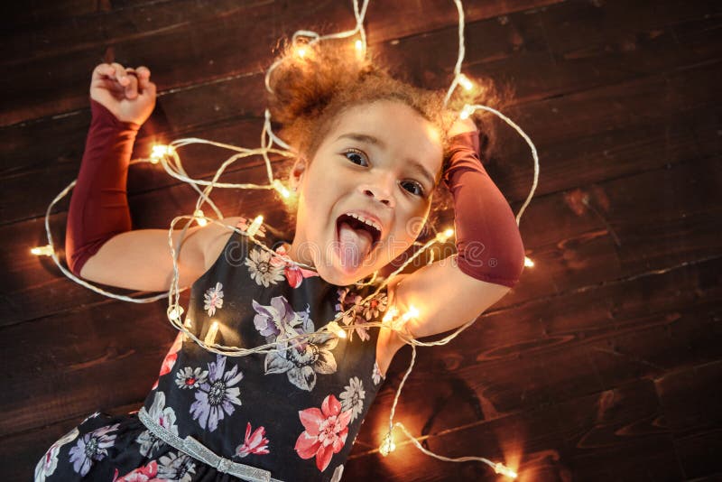 Leuk meisje die op Flor met heldere Kerstmisslinger leggen in haar haar stock foto's Leuk meisje die op Flor met heldere Kerstmisslinger leggen in haar haar stock foto's