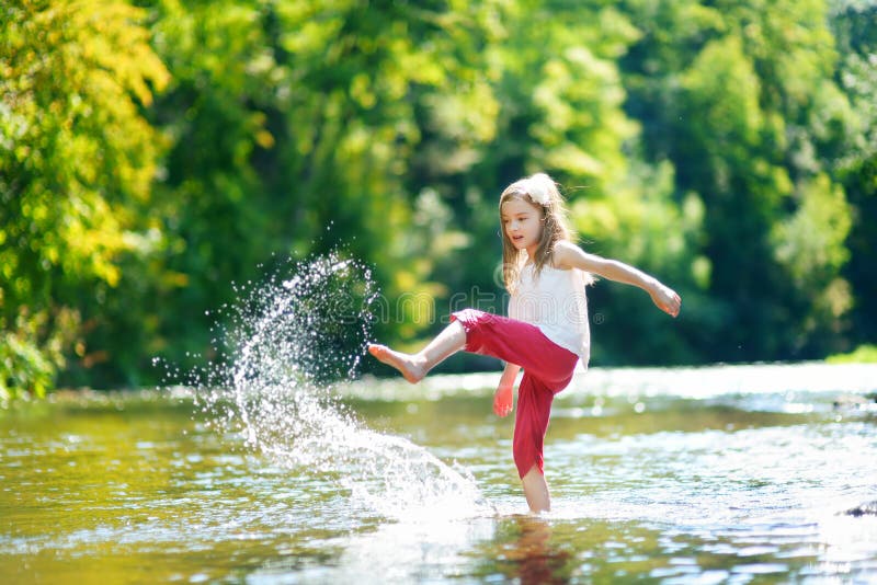 Leuk meisje die pret hebben door een rivier op warme de zomerdag royalty-vrije stock afbeeldingen Leuk meisje die pret hebben door een rivier op warme de zomerdag royalty-vrije stock afbeeldingen