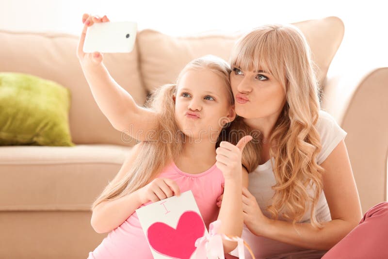 Leuk meisje en haar moeder die selfie met met de hand gemaakte kaart thuis nemen royalty-vrije stock afbeelding Leuk meisje en haar moeder die selfie met met de hand gemaakte kaart thuis nemen royalty-vrije stock afbeelding