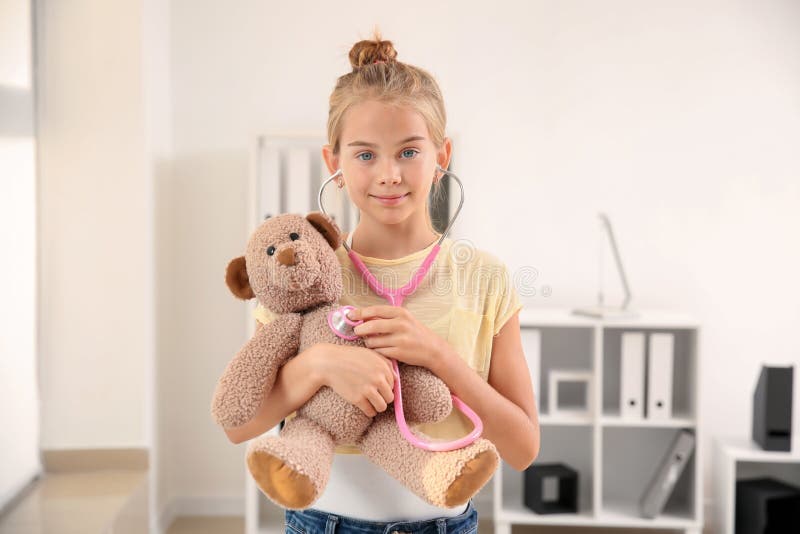 Leuk meisje met stethoscoop en teddybeer thuis royalty-vrije stock fotografie Leuk meisje met stethoscoop en teddybeer thuis royalty-vrije stock fotografie