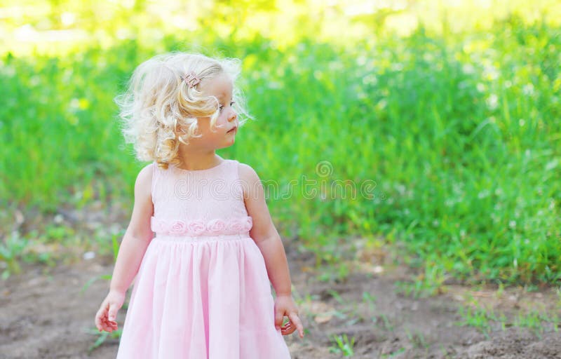 Leuk meisjekind met krullend haar die een roze kleding dragen stock foto Leuk meisjekind met krullend haar die een roze kleding dragen stock foto