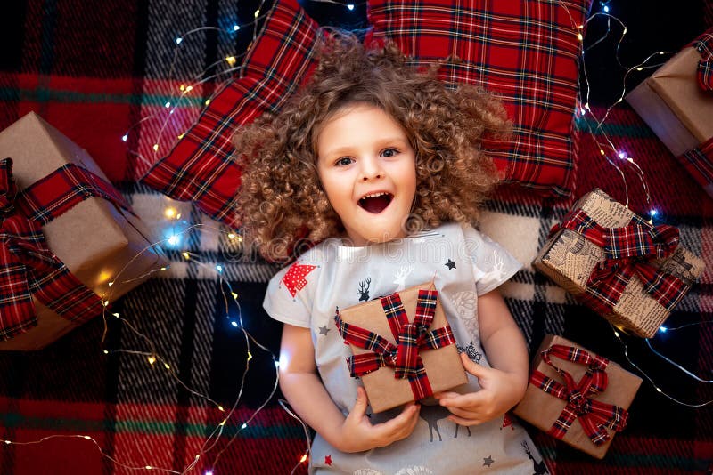 Leuk portret van het glimlachen van weinig kind die in de pyjama's van vakantiekerstmis giftdoos houden Hoogste mening stock fotografie Leuk portret van het glimlachen van weinig kind die in de pyjama's van vakantiekerstmis giftdoos houden Hoogste mening stock fotografie