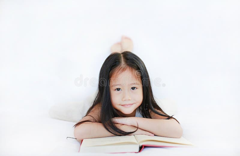 Leuk portret van weinig Aziatisch kindmeisje die een boek lezen die op witte achtergrond liggen royalty-vrije stock foto's Leuk portret van weinig Aziatisch kindmeisje die een boek lezen die op witte achtergrond liggen royalty-vrije stock foto's