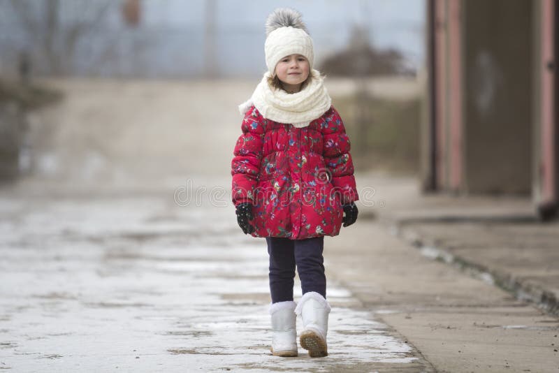 Leuk portret van weinig jong grappig mooi kindmeisje die in aardige warme de winterkleding vol vertrouwen alleen op witte heldere stock foto Leuk portret van weinig jong grappig mooi kindmeisje die in aardige warme de winterkleding vol vertrouwen alleen op witte heldere stock foto