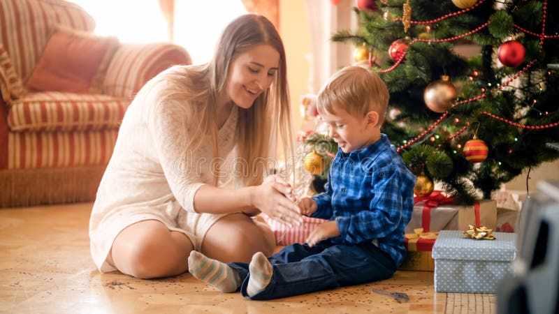 Leuk portret van weinig jongen die pret met moeder op Kerstmisochtend hebben bij woonkamer royalty-vrije stock foto's Leuk portret van weinig jongen die pret met moeder op Kerstmisochtend hebben bij woonkamer royalty-vrije stock foto's